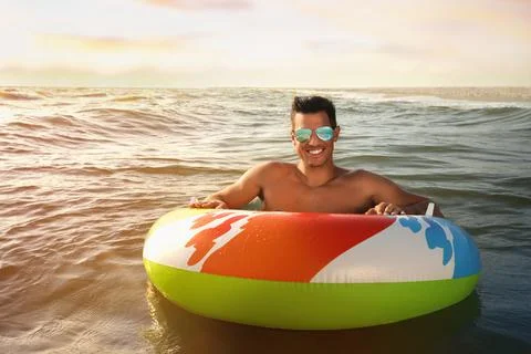 Man with inflatable ring resting in sea 스톡 사진