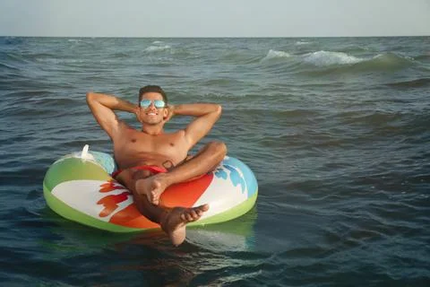 Man with inflatable ring resting in sea 스톡 사진