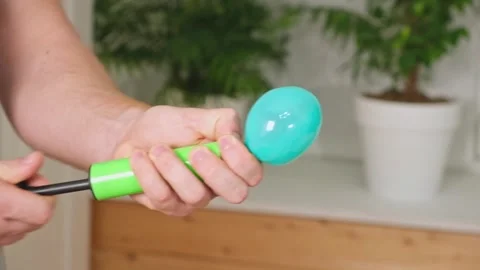 Man inflates a balloon with a pump. Blowing green balloon by hand air pump Stock Footage 242298761