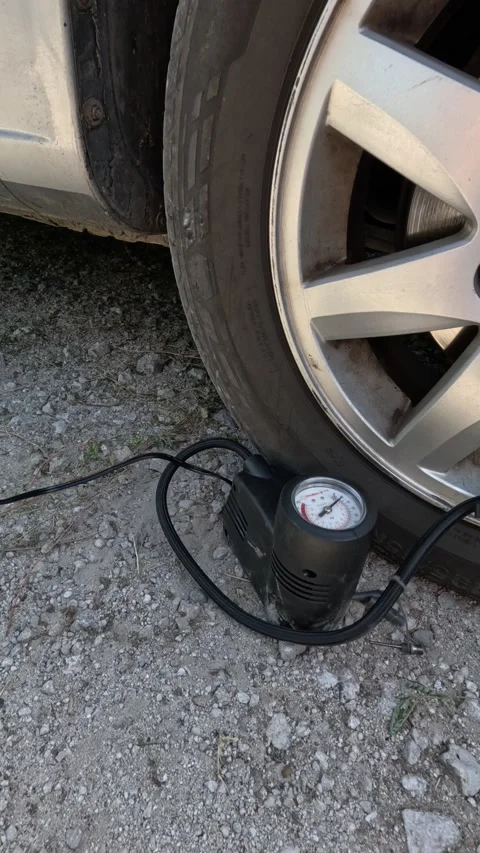A man inflates a car wheel with a compressor. Close-up of a small car air compre Video stock 283807346