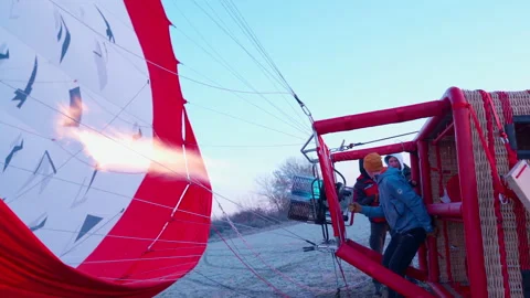 Man inflates large white red hot air balloon dome with flame Stock Footage 146685307