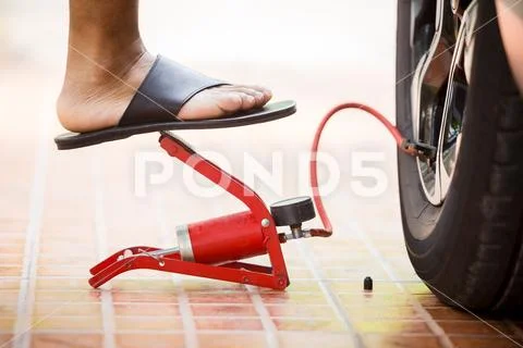 Man Inflating car tyre with foot pump, man put black sandals Inflating car ty Stock Photos