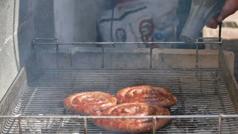 Man inflating fire with a hair phone on a hot coal barbecue griller Stock Footage 139671553