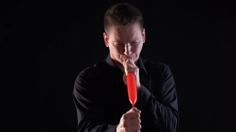Man inflating long balloon by his length isolated on black background Stock Footage 150104144