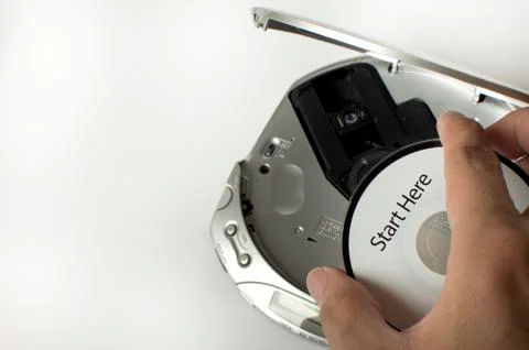 A man is inserting a cd in a cd player with a start here message Stock-Fotos