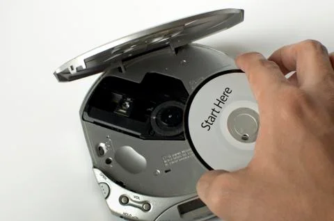 A man is inserting a cd in a cd player with a start here message Stock-Fotos