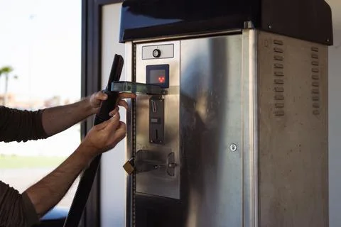 Man inserting coin into a self-service coin-operated vacuum cleaner machine.. Stock Photos