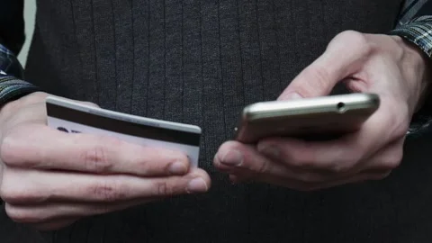 Man inserting credit card number on mobile phone. Online banking with smartphone Stock Footage 101898032