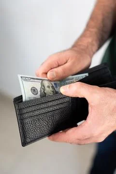 Man inserting dollar bills into wallet Stock Photos
