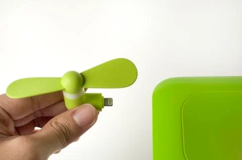 A man is inserting a green mini fan to a power bank Stock-Fotos