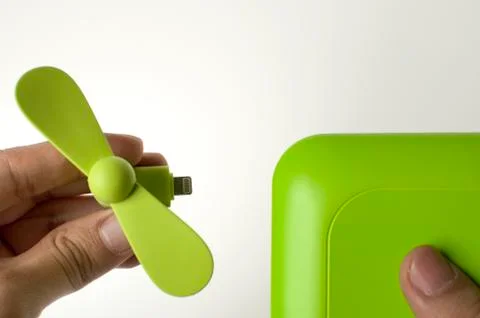 A man is inserting a green mini fan to a power bank Foto stock