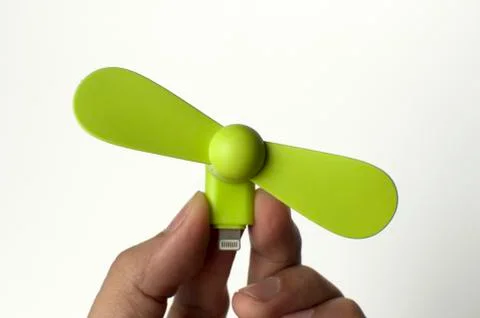 A man is inserting a green mini fan to a power bank Stock-Fotos