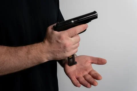 Man inserting loaded magazine into semi automatic pistol close up Fotos Stock