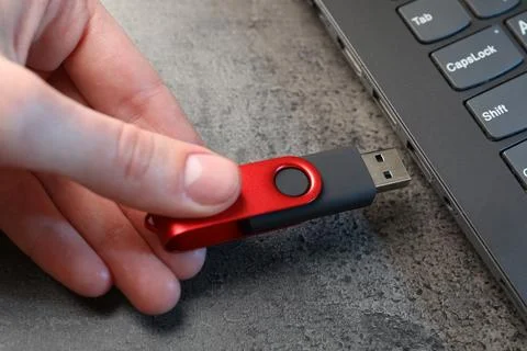 Man inserting modern flash drive at grey table, closeup Stock Photos