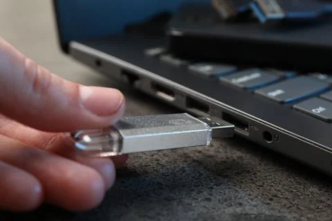 Man inserting modern flash drive at grey table, closeup Stock Photos