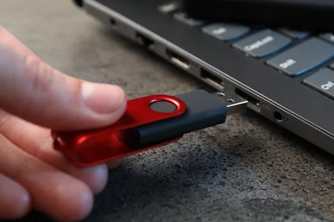 Man inserting modern flash drive at grey table, closeup Foto stock