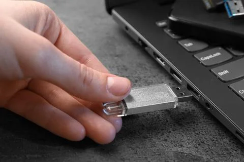 Man inserting modern flash drive at grey table, closeup Foto stock