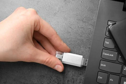 Man inserting modern flash drive at grey table, top view Foto stock