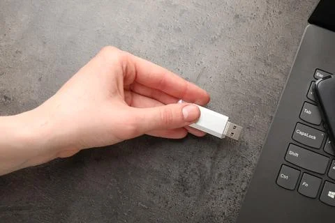 Man inserting modern flash drive at grey table, top view Foto stock