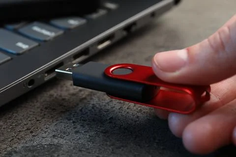 Man inserting modern flash drive at grey table, closeup Foto stock