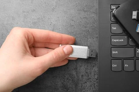Man inserting modern flash drive at grey table, top view Foto stock
