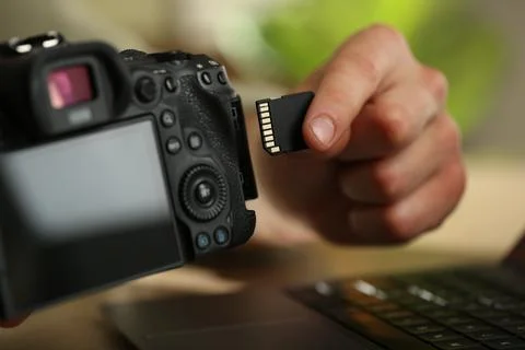 Man inserting SD memory card into photo camera at table, closeup Foto stock