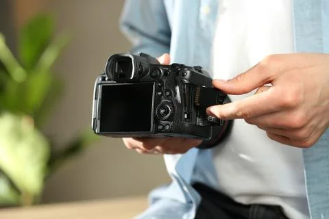 Man inserting SD memory card into photo camera indoors, closeup Stock Photos