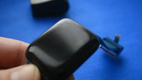A man inserts a charger into a smart watch on dark blue background.Action for Video stock 125589702