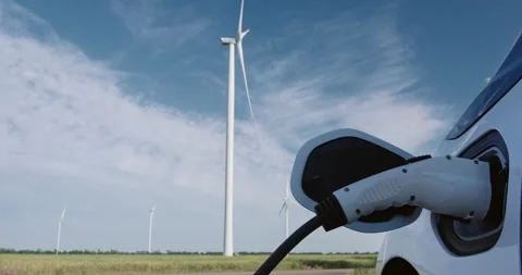 Man inserts charging plug to charge electric car by windmill Stockbeeldmateriaal 160648304