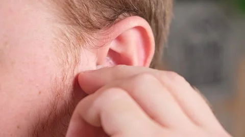 Man inserts earplugs so as not hear extraneous noise, music, snoring. Silicone Stock Footage 236921265