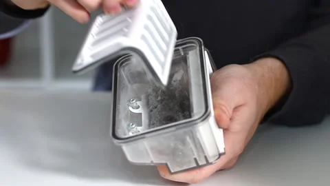A man inserts a filter and a container to collect dust and debris into robot Stock Footage 166105007