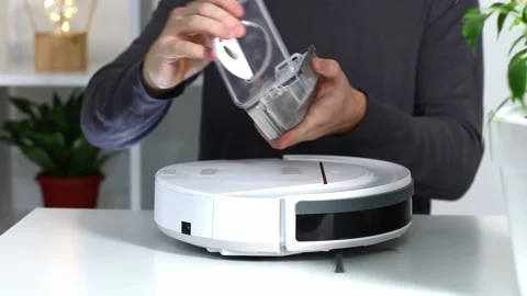 A man inserts a filter and a container to collect dust and debris into robot Stock Footage 166105026