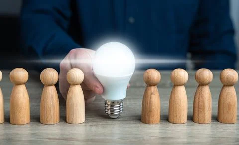 A man inserts a glowing light bulb idea between people. Inspire society to ne Fotos Stock