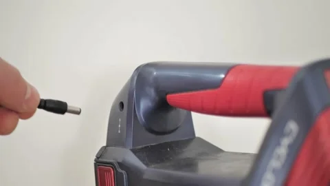 The man inserts the plug of the charger into a vacuum cleaner with a battery. Stock Footage 194018044