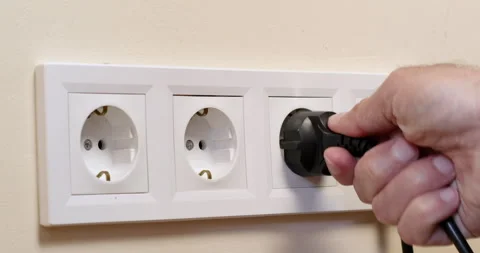 Man inserts plug from domestic appliance into white socket Stock-Footage 199913336