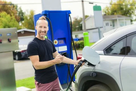 Man inserts plug into the electric car charging socket Stock-Fotos