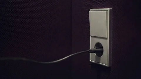 The man inserts the plug into the electrical outlet Stock Footage 76481036