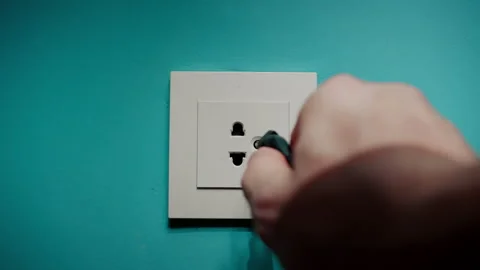Man Inserts Plug Into Electrical Socket On A Blue Wall Stock Footage 196950976