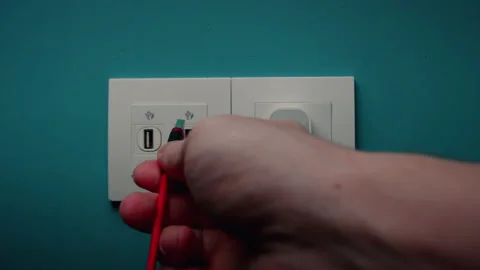 Man Inserts Plug Into Electrical Socket On A Blue Wall Video stock 197371269