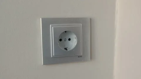 Man inserts plug into Electrical socket on a wall Stock Footage 202188824