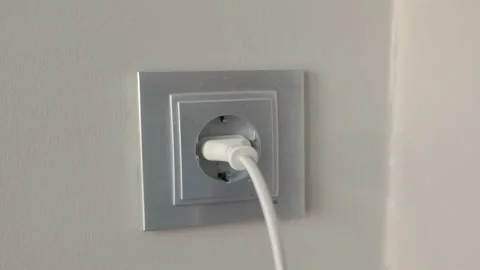 Man inserts plug into Electrical socket on a wall Stock Footage 202188829
