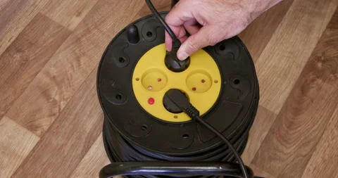Man inserts plugs into extension cord socket on room floor closeup 스톡 동영상 259031322