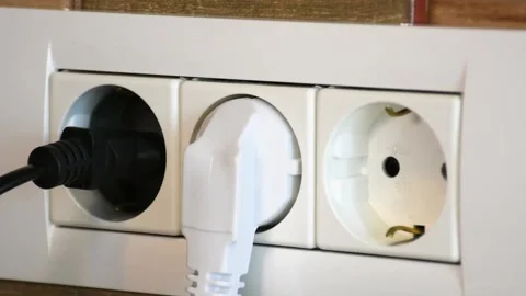 Man inserts power cables into electrical wall socket. 動画素材 141169539