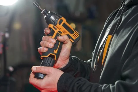 A man inserts a replacement battery into an electric wrench Stock Photos