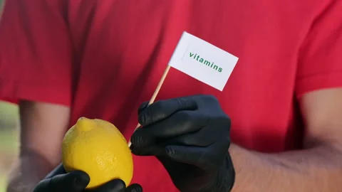 Man inserts a sign that says "vitamins" into a fresh lemon Stock Footage 141864211