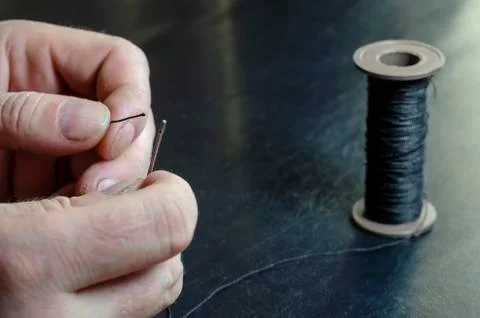 The man inserts the thread into the eye of the needle. Stockfoto's