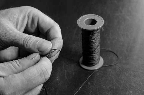 The man inserts the thread into the eye of the needle. Foto stock