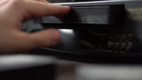 A man inserts a video cassette into a VCR Video stock 234407620