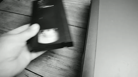 Man inserts videotape into video cassette recorder, black and white Stock Footage 138143772
