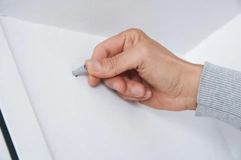 A man inserts a wall plug into a drilled hole Stock Photos